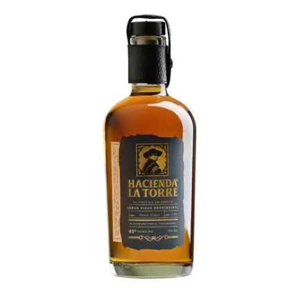 Botella de Pisco Hacienda La Torre Envejecido 43° 700cc, ámbar profundo, con etiqueta negra y detalles dorados.